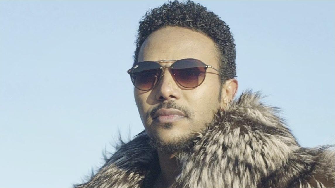 Still from the Endaymesh music video: Milly Wessy in sunglasses and a fur collar against a pale sky