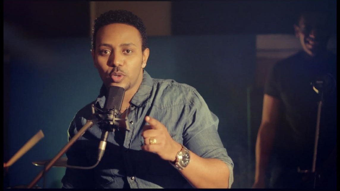 Still from the Min Yegermal music video: Milly Wessy at a studio microphone