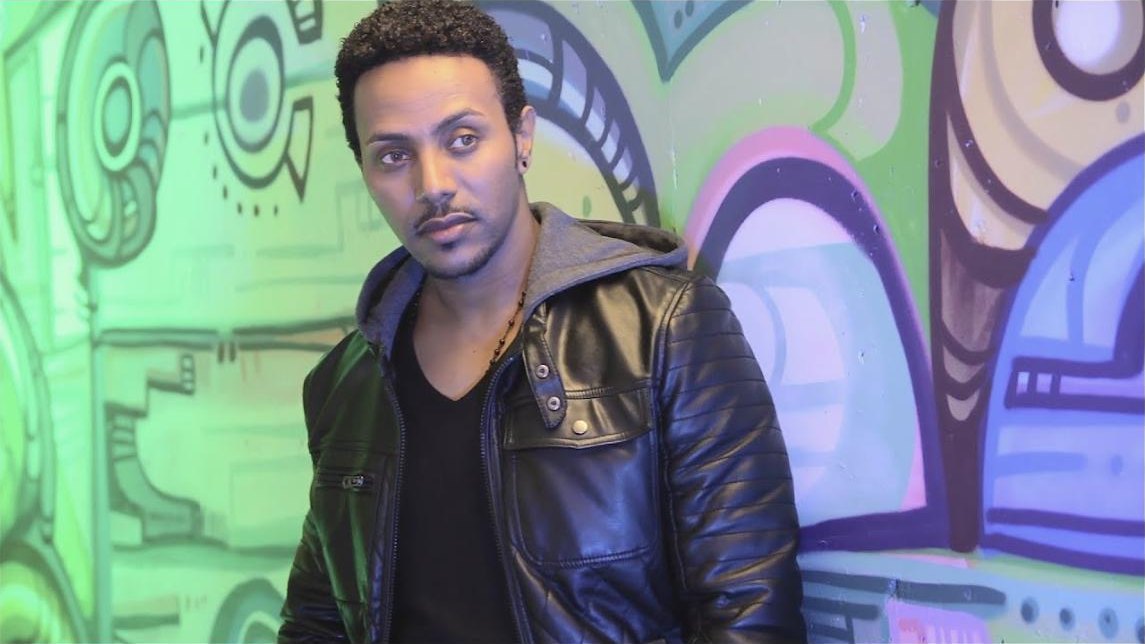 Still from the Shemshirshaye music video: Milly Wessy in a leather jacket against a painted wall